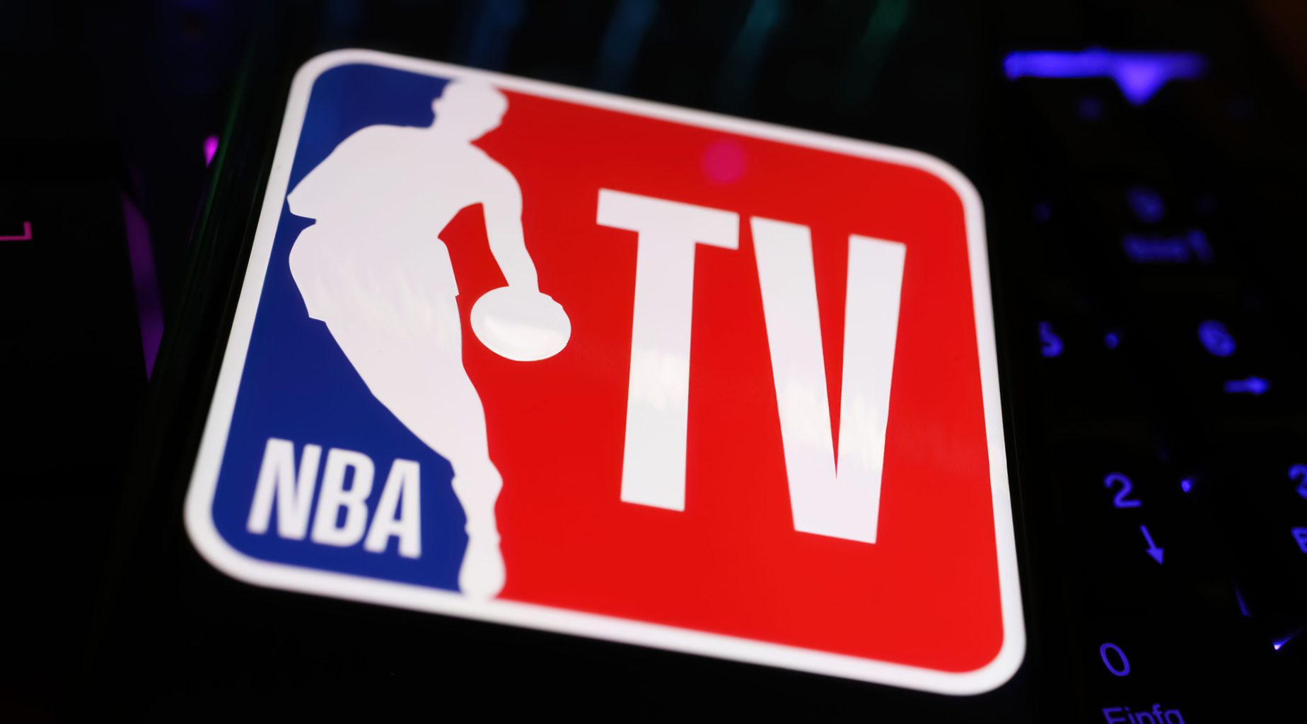 Application NBA TV affichée sur un smartphone posé sur un clavier d'ordinateur
